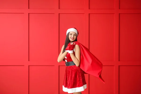 Mulher bonita com saco de Papai Noel perto da parede de cor — Fotografia de Stock