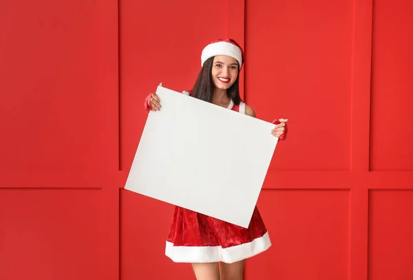サンタクロースの衣装の美しい若い女性と色の壁の近くに空白のポスター — ストック写真