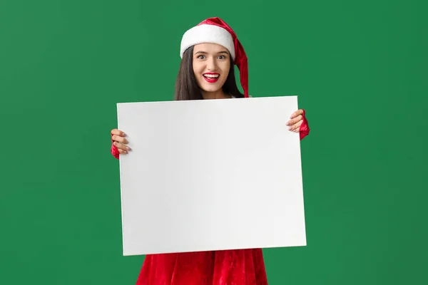 Mulher bonita em traje de Papai Noel e com cartaz em branco sobre fundo de cor — Fotografia de Stock