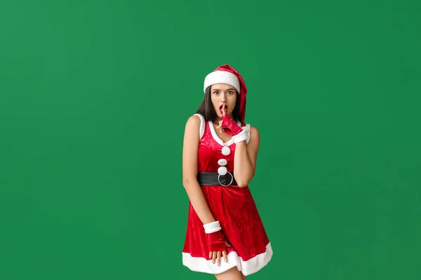 Hermosa mujer joven en traje de Santa Claus mostrando gesto de silencio en el fondo de color — Foto de Stock