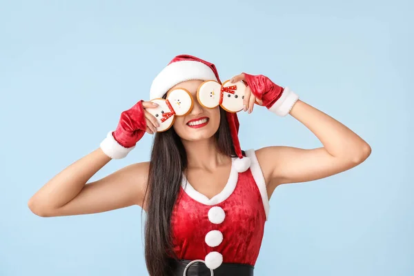 Belle jeune femme en costume de Père Noël et avec des biscuits de Noël sur fond clair — Photo