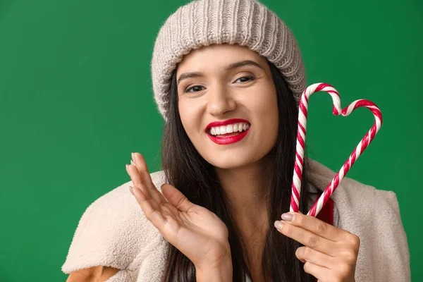 Belle jeune femme en vêtements d'hiver et avec des cannes de bonbons sur fond de couleur — Photo