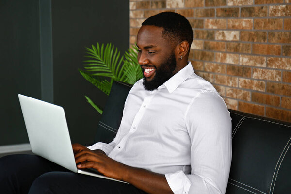 Handsome African-American businessman working on laptop in office