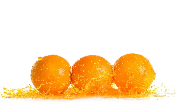 Спелые апельсины и брызги сока на белом фоне — стоковое фото