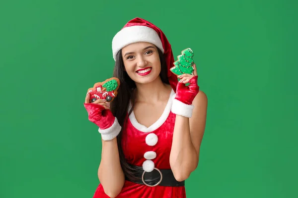 Bella giovane donna in costume di Babbo Natale e con biscotti di Natale su sfondo di colore — Foto Stock
