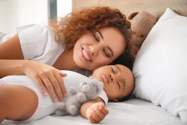 Joven mujer afroamericana y su bebé durmiendo en la cama — Foto de Stock