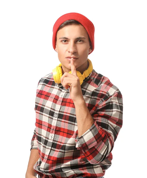 Portrait of handsome young man with headphones showing silence gesture on white background — Stock Photo, Image