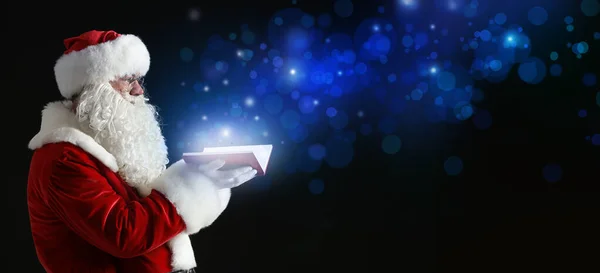 Santa Claus with magic book on dark background — Stock Photo, Image