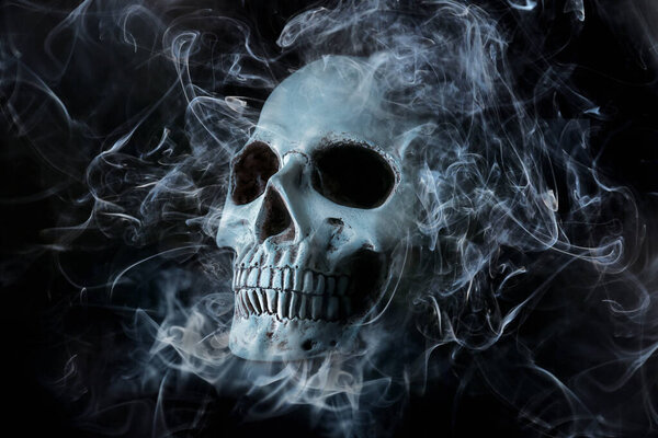 Human skull with smoke on dark background