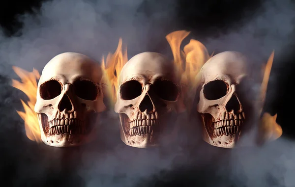 Menselijke schedels met vlam en rook op donkere achtergrond — Stockfoto