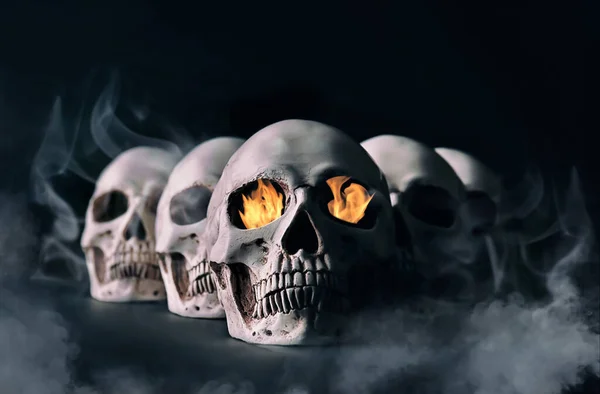 Crânios humanos com chama e fumaça no fundo escuro — Fotografia de Stock