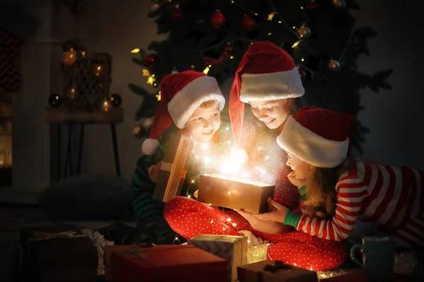 Söta små barn öppnar magiska julklapp hemma — Stockfoto