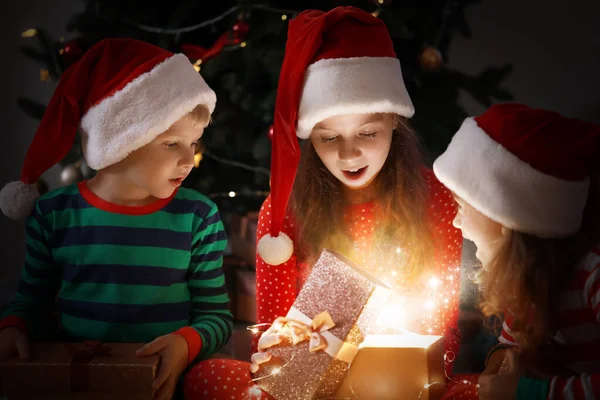 Śliczne małe dzieci otwierające magiczny świąteczny prezent w domu — Zdjęcie stockowe