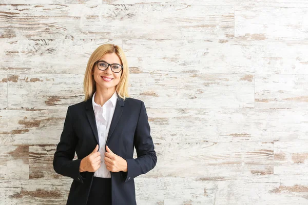 Beautiful stylish businesswoman against wooden wall — Stock Photo, Image