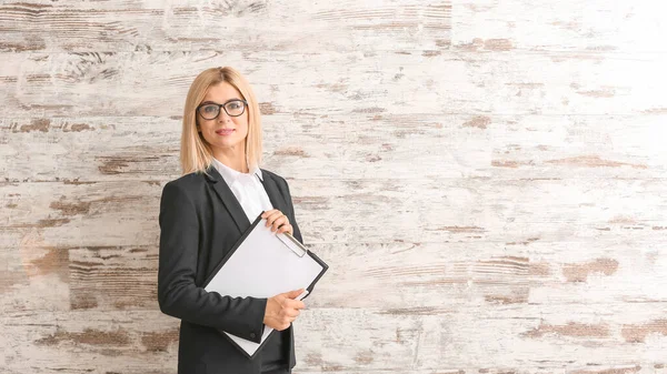 Belle femme d'affaires élégante avec presse-papiers contre le mur en bois — Photo