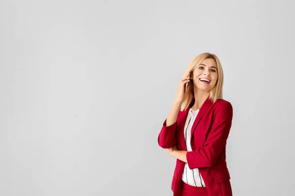 Hermosa mujer de negocios elegante hablando por teléfono sobre fondo claro — Foto de Stock