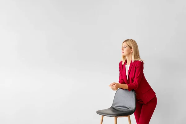 Mulher de negócios elegante bonita com cadeira no fundo claro — Fotografia de Stock