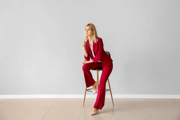 光の壁に椅子に座っている美しいスタイリッシュなビジネス女性 — ストック写真
