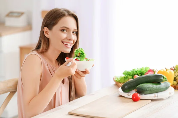 Jonge vrouw die gezonde groentesalade eet in de keuken. Dieetconcept — Stockfoto