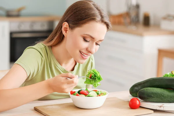 Jonge vrouw die gezonde groentesalade eet in de keuken. Dieetconcept — Stockfoto