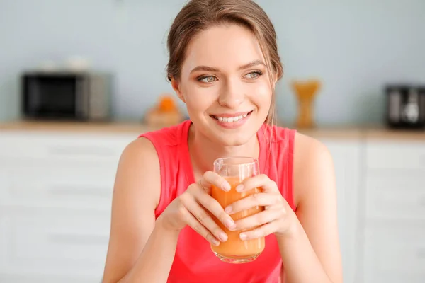 Jonge vrouw die gezond sap drinkt in de keuken. Dieetconcept — Stockfoto