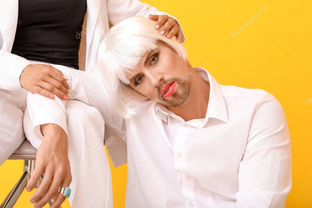 Young transgender woman with girlfriend on color background
