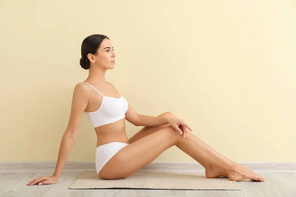 Hermosa joven sentada cerca de la pared de color. Concepto de depilación — Foto de Stock