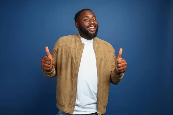 Happy African-American man showing thumb-up gesture on color background — Stock Photo, Image