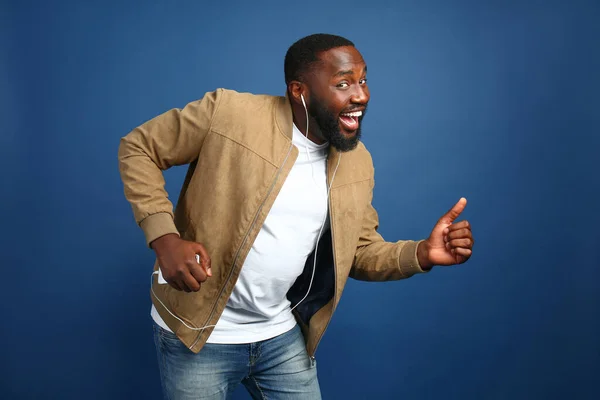 Happy African-American man listening to music on color background — Stock Photo, Image