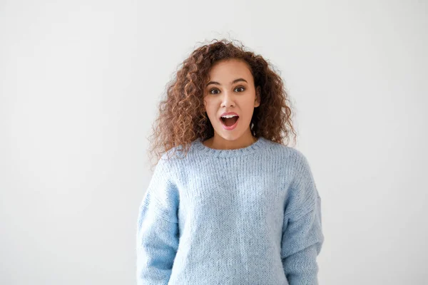 Portrait of surprised young African-American woman on light background — Stock Photo, Image