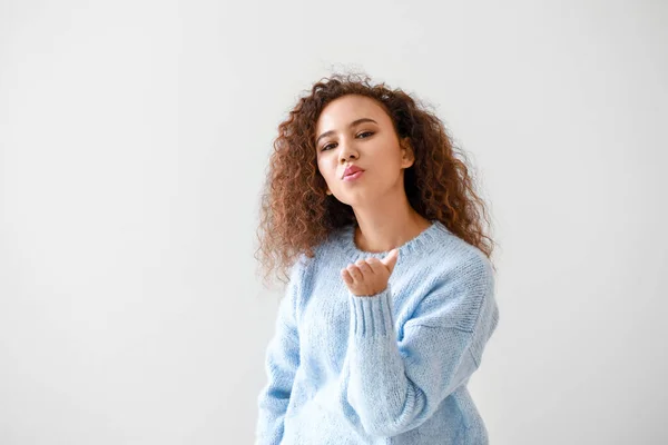 Ritratto di giovane donna afro-americana che soffia bacio su sfondo chiaro — Foto Stock