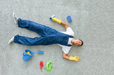 Yorgun genç adam, üst kattaki daireyi temizledikten sonra yerde yatıyor.