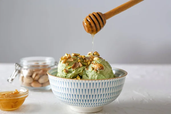 Goteo de miel en el sabroso helado de pistacho en un tazón sobre una mesa blanca —  Fotos de Stock