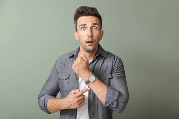 Stressed young man with watch on color background — Stock Photo, Image