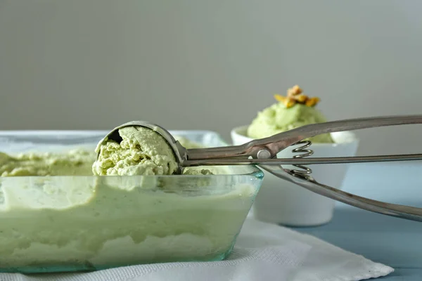 Bandeja con sabroso helado de pistacho y cucharada en la mesa —  Fotos de Stock
