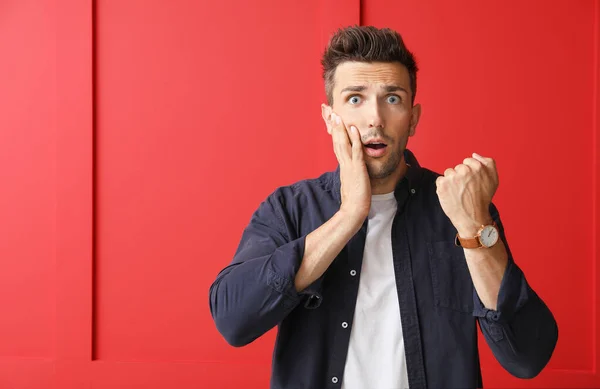 Stressé jeune homme avec montre sur fond de couleur — Photo