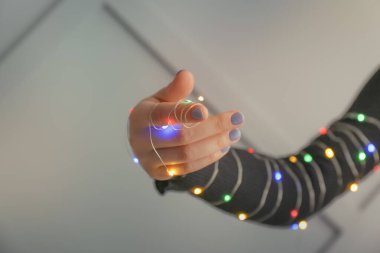 Gri arka planda parıldayan bir çelengi olan kadın eli.