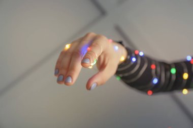 Gri arka planda parıldayan bir çelengi olan kadın eli.