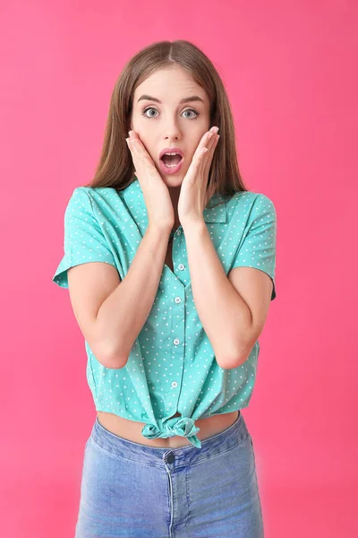 Überraschte junge Frau auf farbigem Hintergrund — Stockfoto