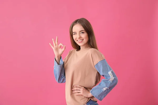 Vacker ung kvinna som visar OK på färg bakgrund — Stockfoto