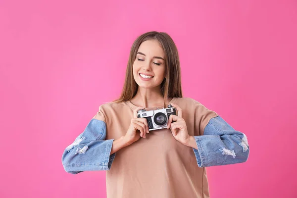 Mooie jonge vrouw met fotocamera op kleur achtergrond — Stockfoto