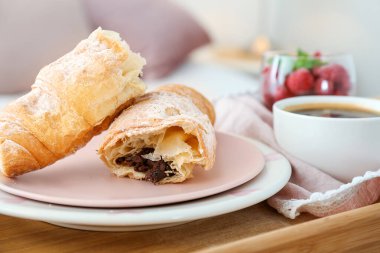 Lezzetli kruvasan, sehpanın üzerinde bir fincan kahve, yakın plan.