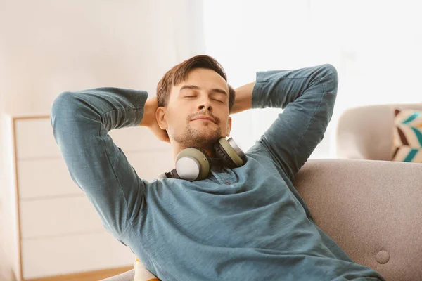 Hombre guapo con auriculares relajante en casa —  Fotos de Stock