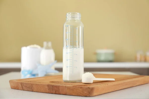 Bottle of baby milk formula on table in kitchen