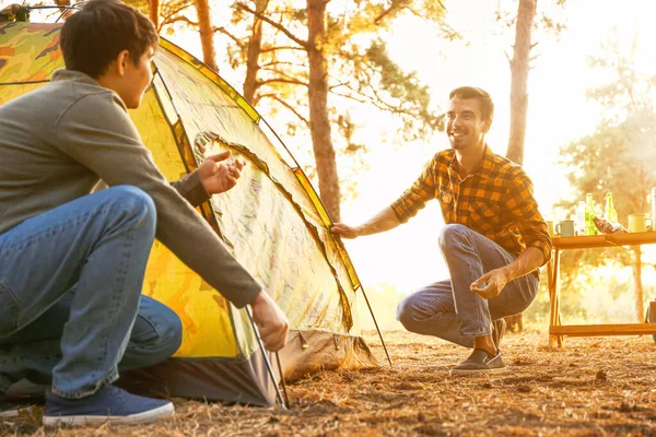 Friends putting up camping tent in forest — Stock Photo, Image