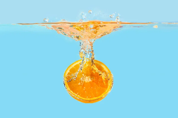 Açık arkaplanda portakal yarısının suya düşmesi — Stok fotoğraf