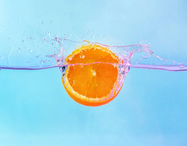 Queda de pedaço de laranja na água no fundo claro — Fotografia de Stock