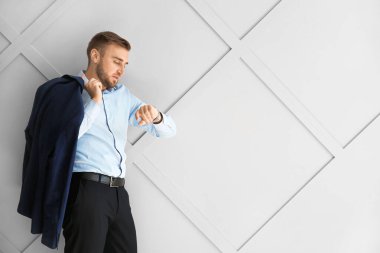 Işık arkaplanındaki saate bakan yakışıklı iş adamının portresi