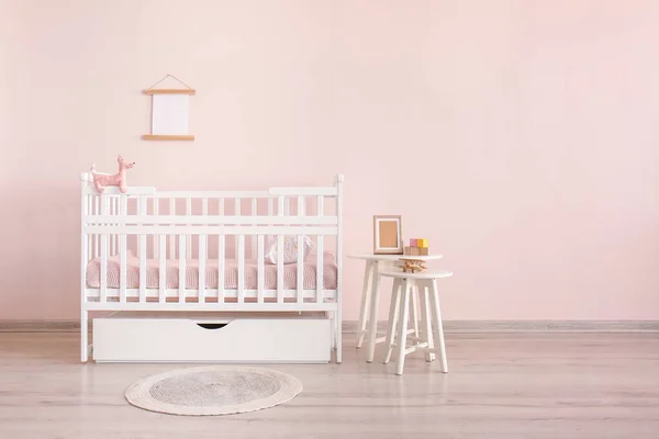 Stylish baby bed with table near color wall in interior of children's room — Stock Photo, Image
