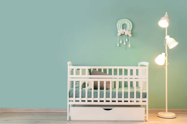 Stylish baby bed with lamp near color wall in interior of children's room — Stock Photo, Image